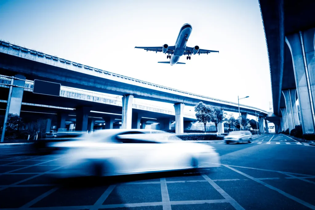 avion qui survole un aéroport avec des voiture en circulation